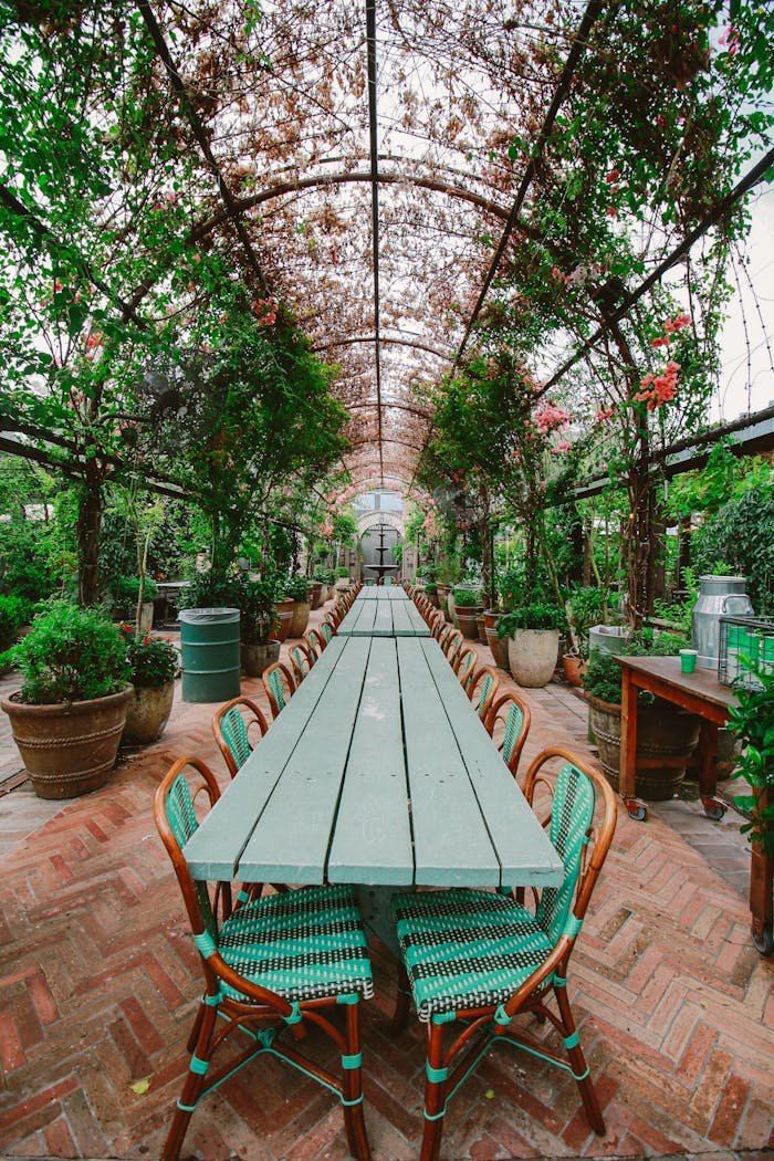 Long table under a lush floral archway, perfect for outdoor dining in a serene garden setting.